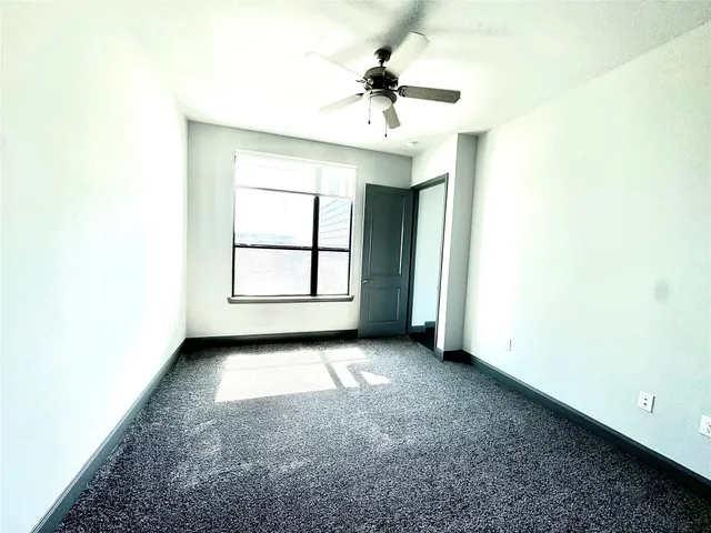 an empty room with windows and ceiling fan