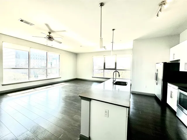 a kitchen with stainless steel appliances granite countertop a sink a stove and a wooden floors