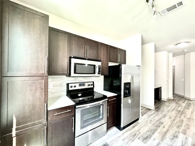 a kitchen with stainless steel appliances kitchen island granite countertop a refrigerator a stove and a sink