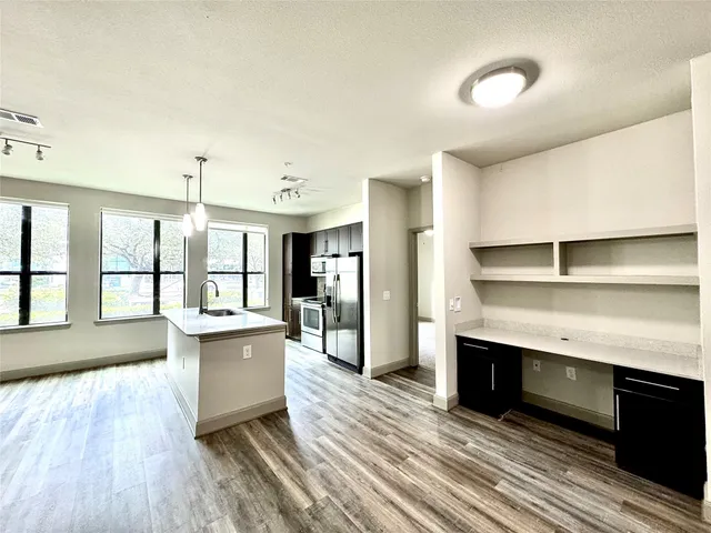 a large kitchen with stainless steel appliances a large counter top a stove and a wooden floors