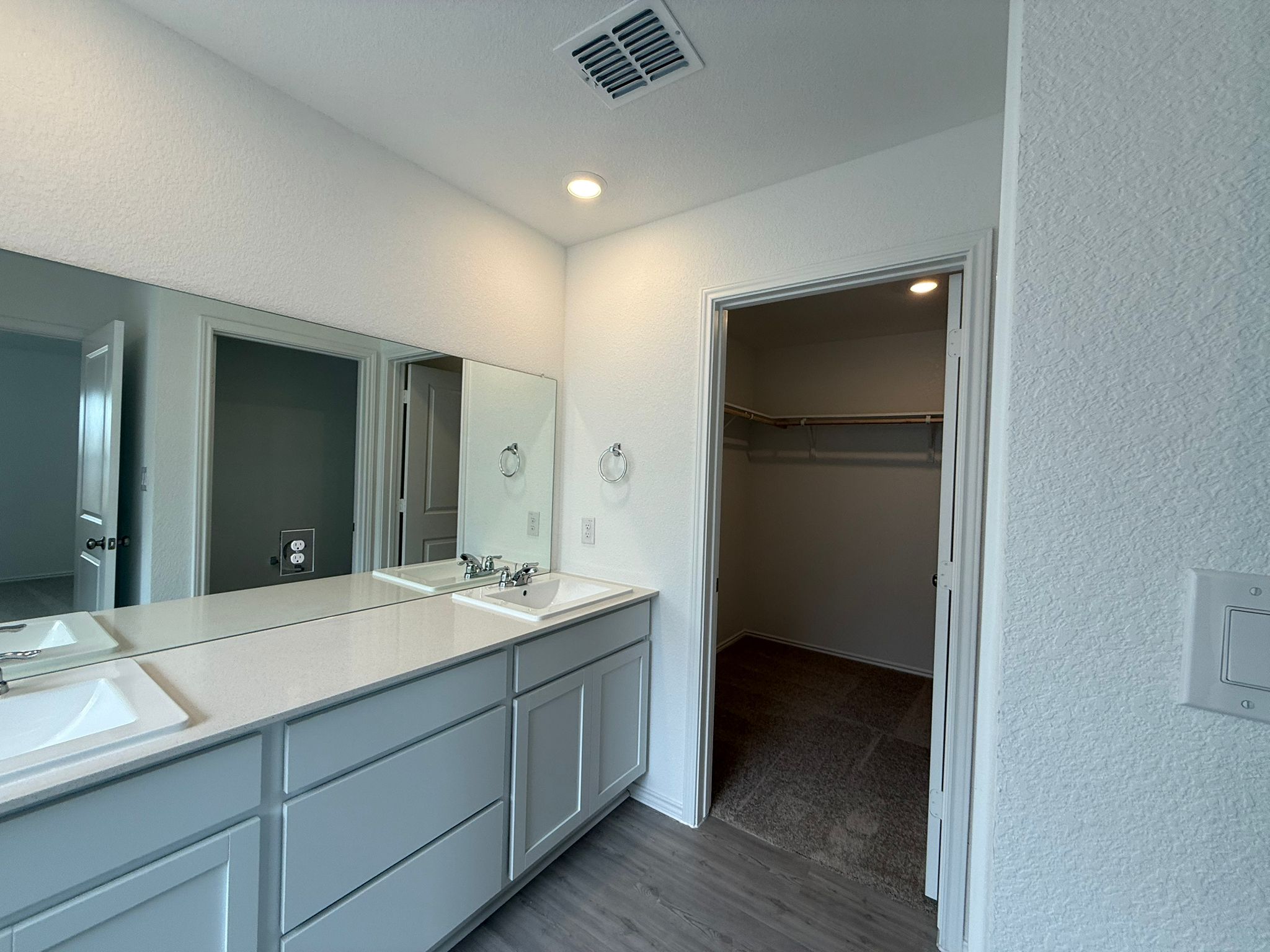 125 Sormonne Loop Kyle, TX 78640 - Photo 25 of 35 Full bath featuring double vanity, wood finished floors, a walk in closet, and a textured wall