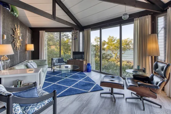 a living room with furniture a flat screen tv and a floor to ceiling window