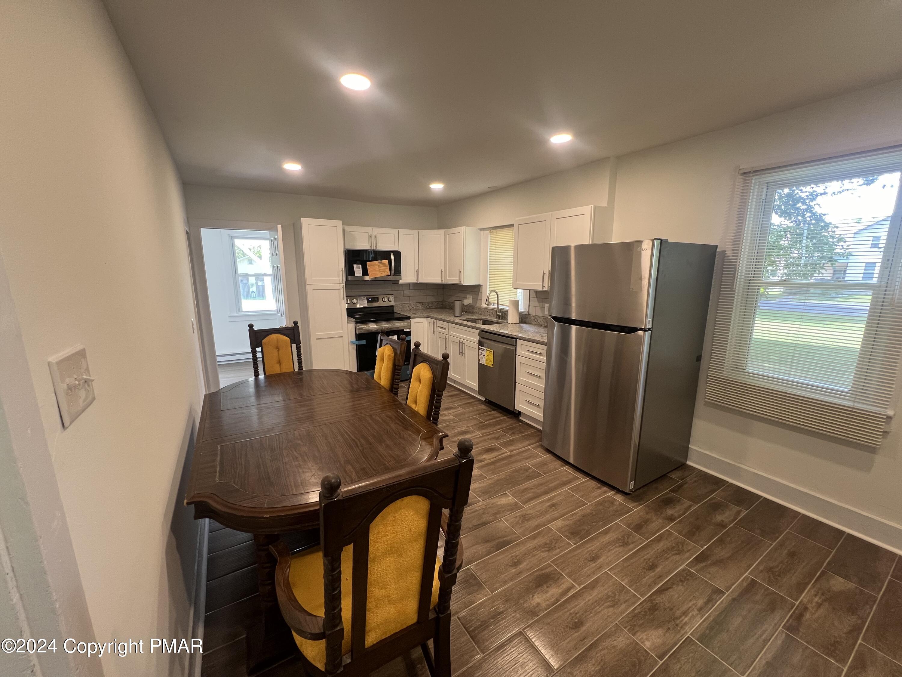 514 Fairground Road Gilbert, PA 18331 - Photo 8 of 20 a kitchen with stainless steel appliances granite countertop a refrigerator a stove a sink a dining table and chairs with wooden floor