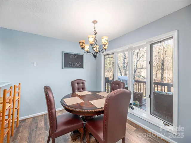a view of a dining room with furniture a chandelier and large windows