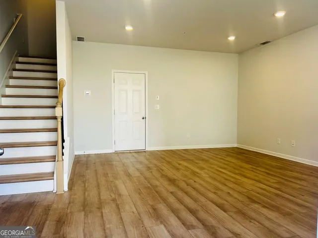 a view of an empty room with wooden floor and stairs