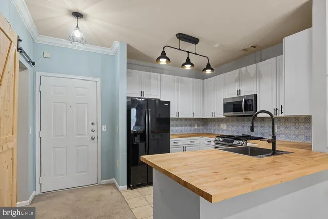 a kitchen with stainless steel appliances granite countertop a refrigerator a stove a sink a microwave and wooden cabinets