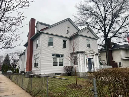 a white house that has a tree in front of it