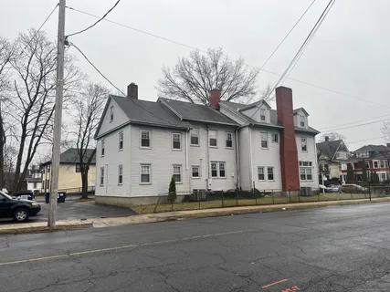 a view of a white house with a large tree