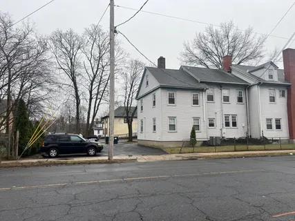 a view of a white house with a large tree