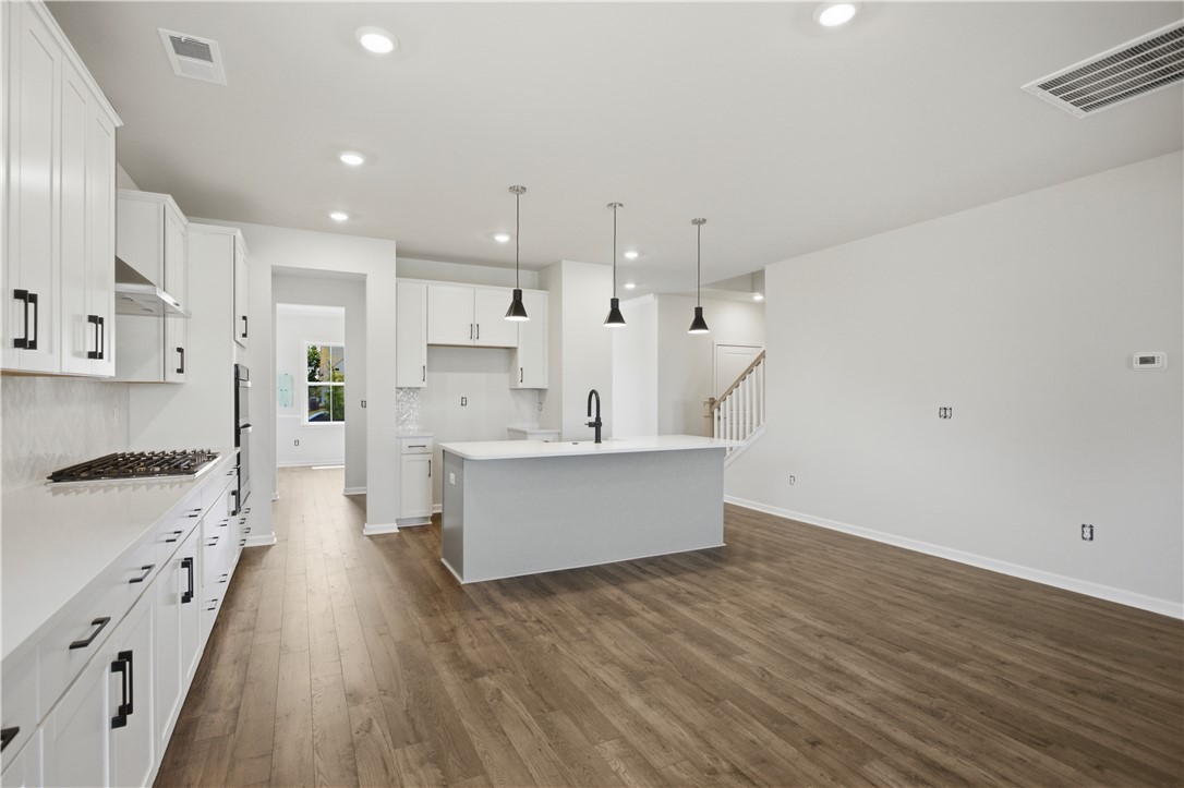 552 Hydrangea Street, Unit LOT 66 Seneca, SC 29678 - Photo 9 of 31 A well-appointed kitchen featuring a substantial island, sleek white cabinetry, and rich hardwood flooring.