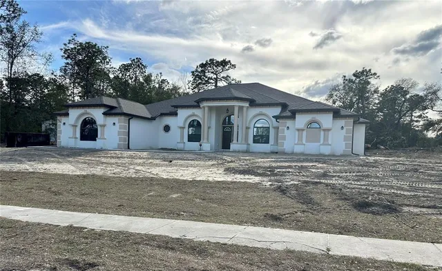 a view of a white house with a yard and large trees