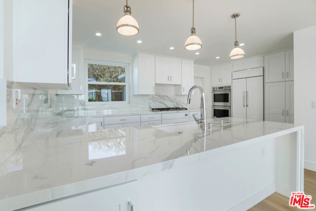 7263 Birdview Avenue Malibu, CA 90265 - Photo 4 of 17 a large kitchen with granite countertop a large kitchen island white cabinets and stainless steel appliances