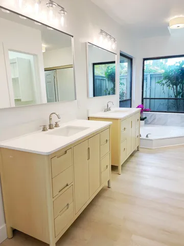 a bathroom with a double vanity sink mirror and a bathtub