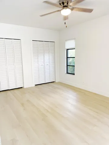an empty room with a ceiling fan and windows