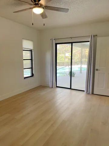 an empty room with windows and ceiling fan