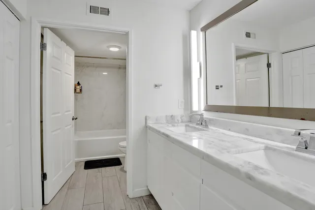 a bathroom with a double vanity sink a vanity and a large mirror