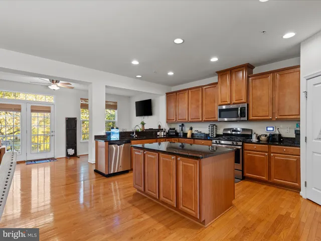a kitchen with kitchen island granite countertop wooden floors and stainless steel appliances