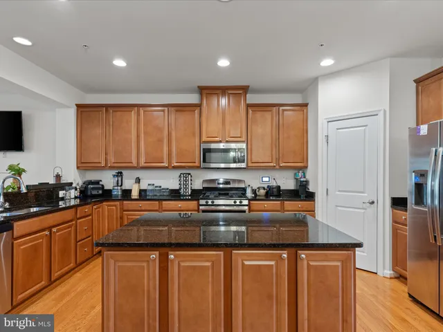 a kitchen with stainless steel appliances granite countertop a stove a sink a refrigerator and cabinets