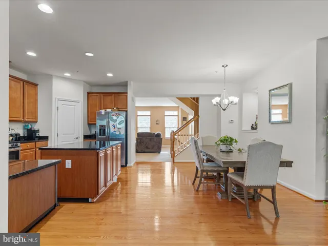 a open kitchen with stainless steel appliances granite countertop a stove top oven a dining table and chairs with wooden floor