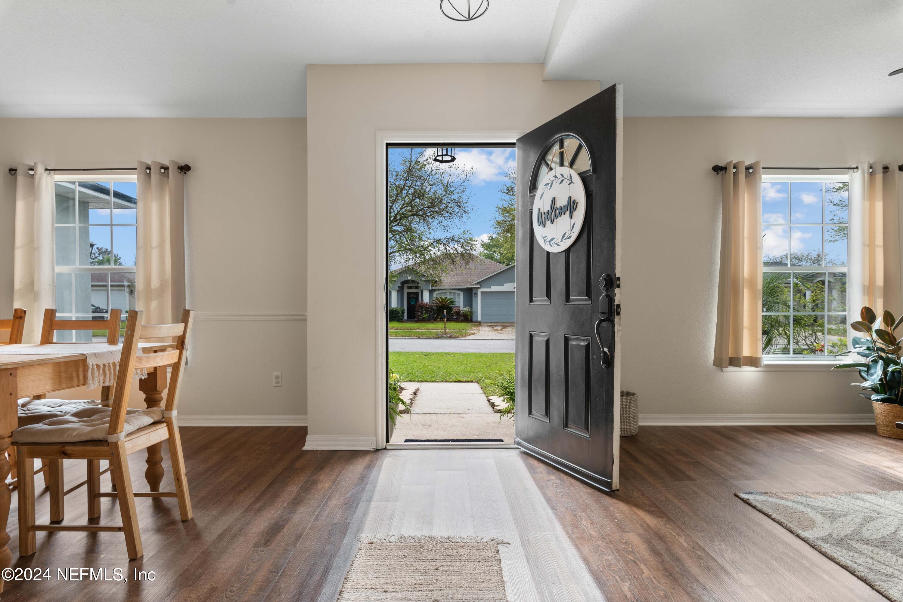 968 Deer Spring Drive Jacksonville, FL 32221 - Photo 7 of 31 a view of a hallway with wooden floor and a dining area with furniture window wooden floor and a clock