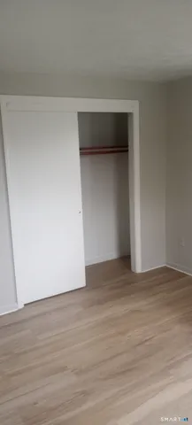 a view of an empty room with wooden floor and closet