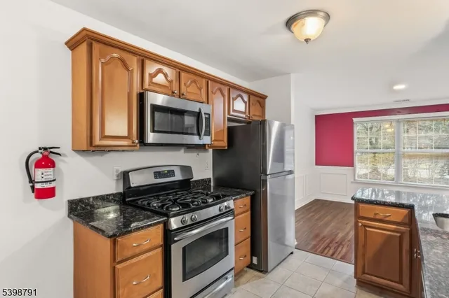 a kitchen with stainless steel appliances granite countertop a stove top oven a refrigerator and a microwave