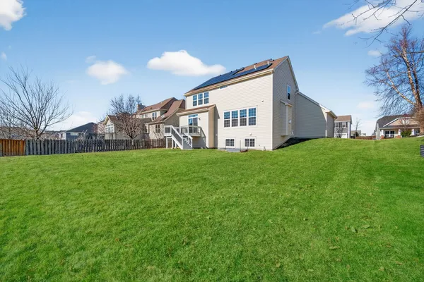 a view of a house with a yard and that has a car
