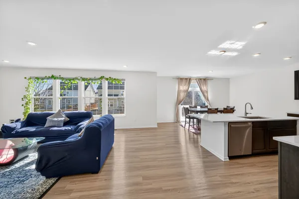 a living room with furniture a large window and wooden floor