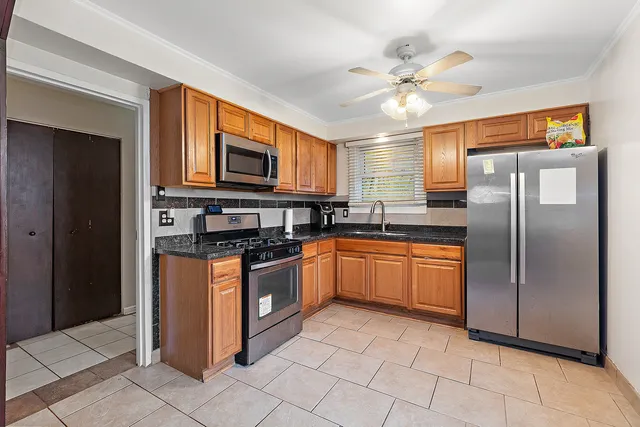 a kitchen with stainless steel appliances granite countertop a refrigerator a sink a stove top oven and a refrigerator