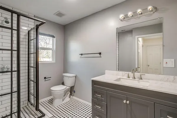 a bathroom with a sink a toilet a mirror and shower