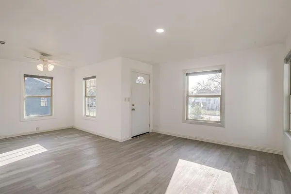 an empty room with wooden floor and windows