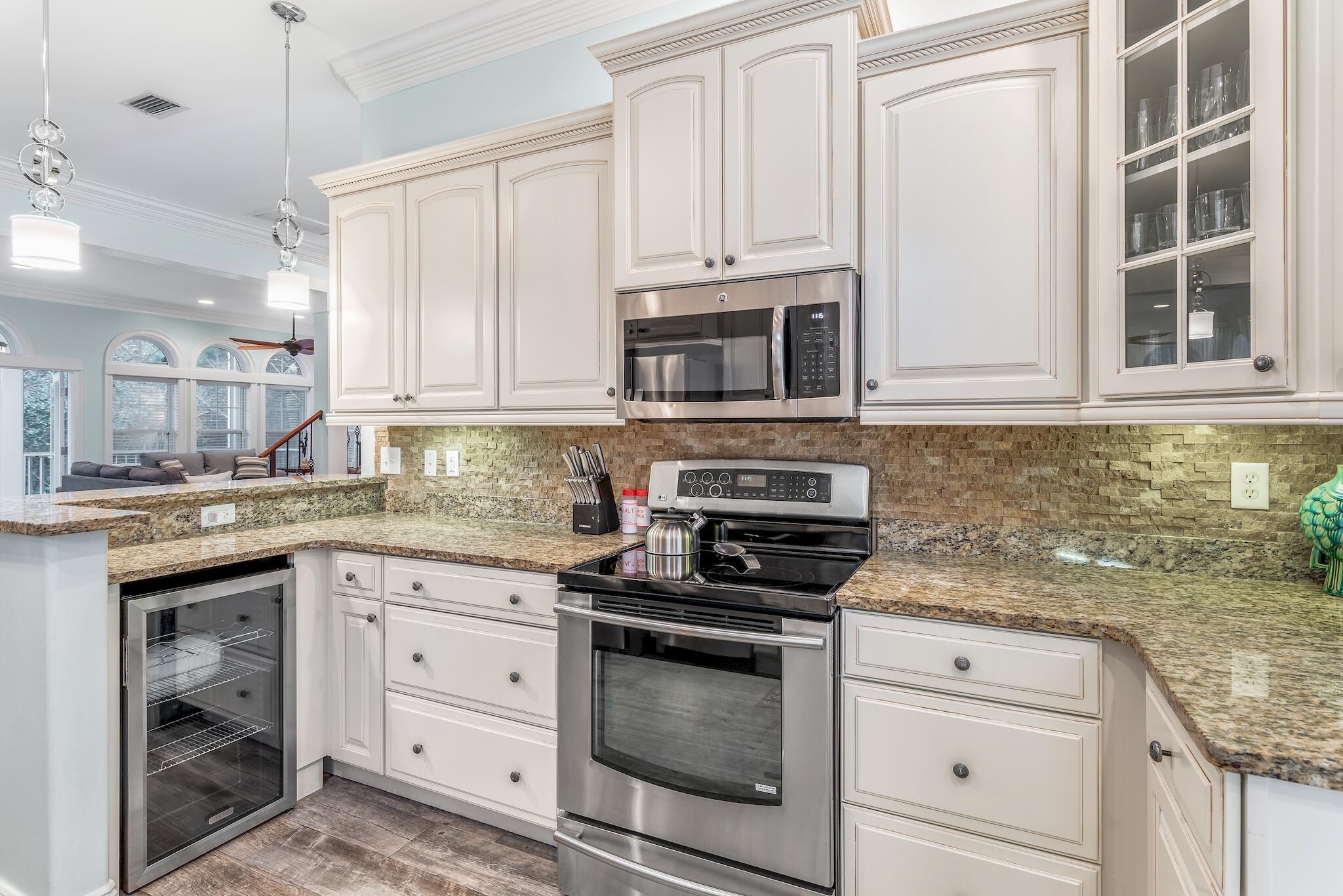 55 The Greenway Loop Panama City Beach, FL 32461 - Photo 5 of 32 a kitchen with granite countertop white cabinets stainless steel appliances and a sink