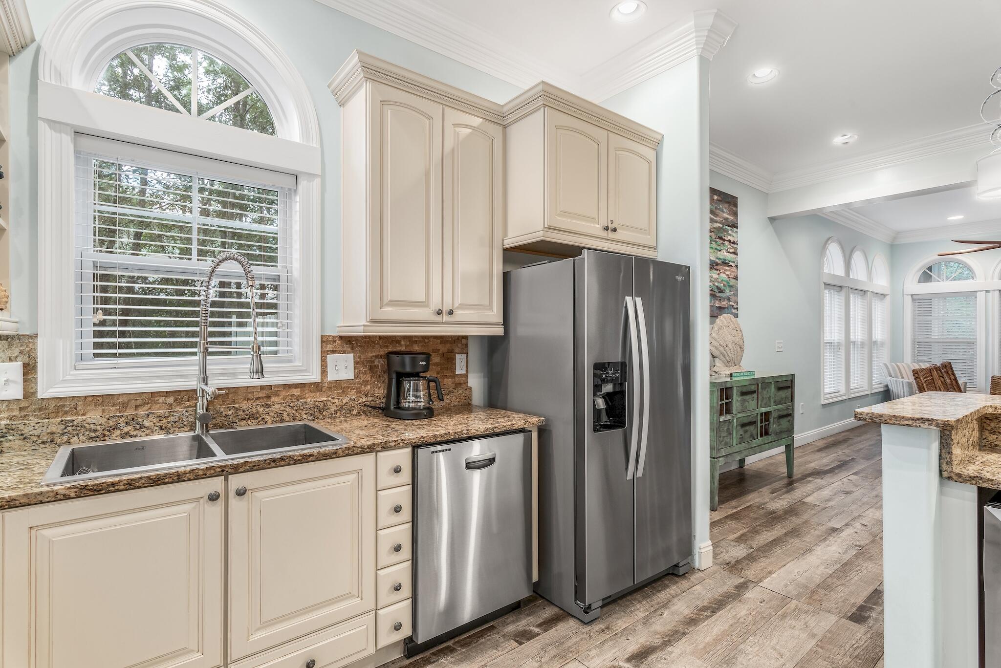 55 The Greenway Loop Panama City Beach, FL 32461 - Photo 6 of 32 a kitchen with stainless steel appliances granite countertop a refrigerator a sink a stove and white cabinets with wooden floor