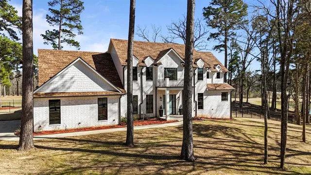 a view of a white house with large windows and a small yard