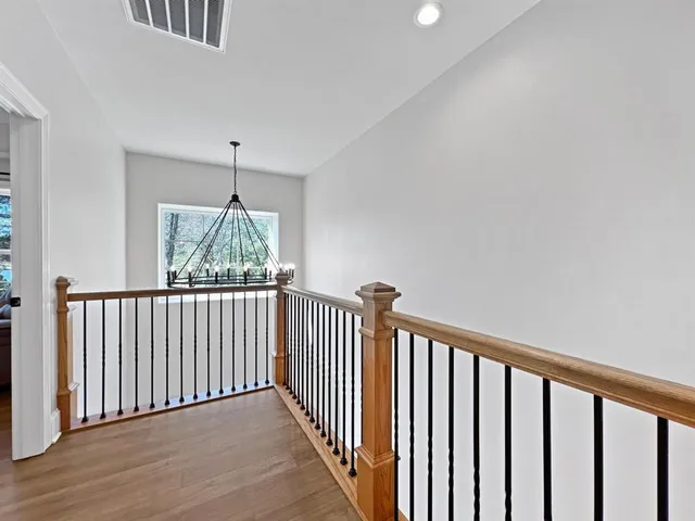 a view of a hallway with wooden floor and a chandelier