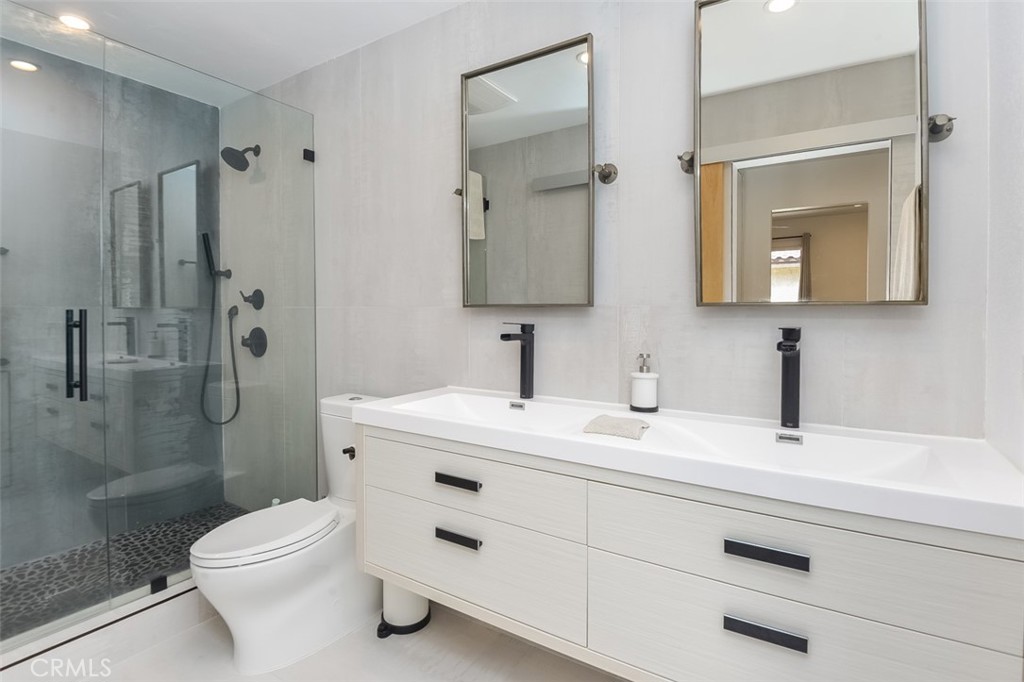 13708 Ruette Le Parc, Unit E Del Mar, CA 92014 - Photo 4 of 30 a bathroom with a toilet a sink a glass door a shower a mirror a vanity and shower