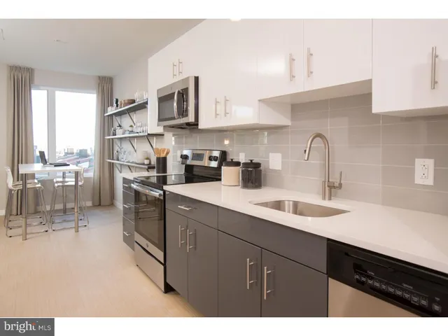 a kitchen with a sink and a large mirror next to a window