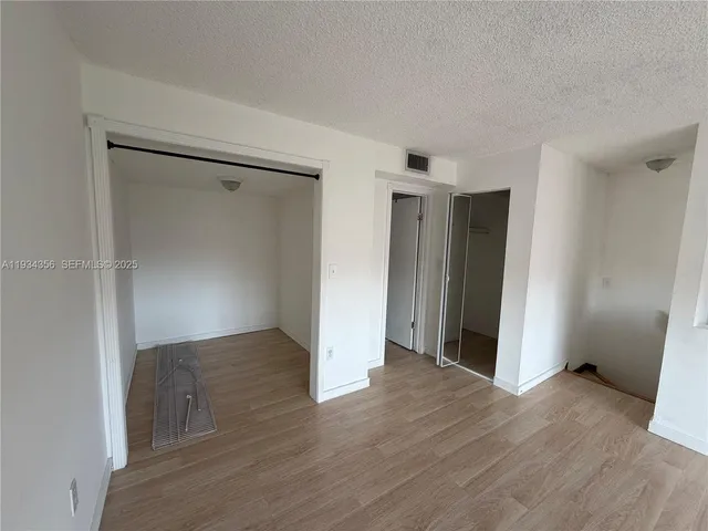 an empty room with wooden floor & closet area