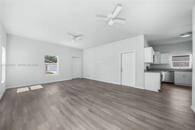 an empty room with wooden floor and a ceiling fan
