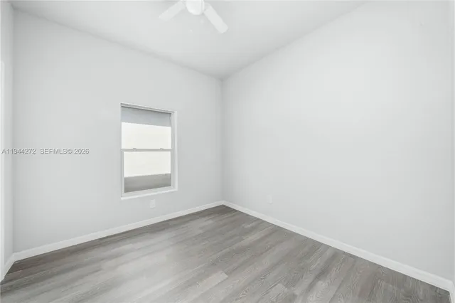 an empty room with wooden floor and a ceiling fan
