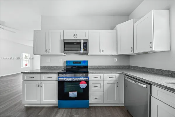an empty room with wooden floor chandelier fan and windows