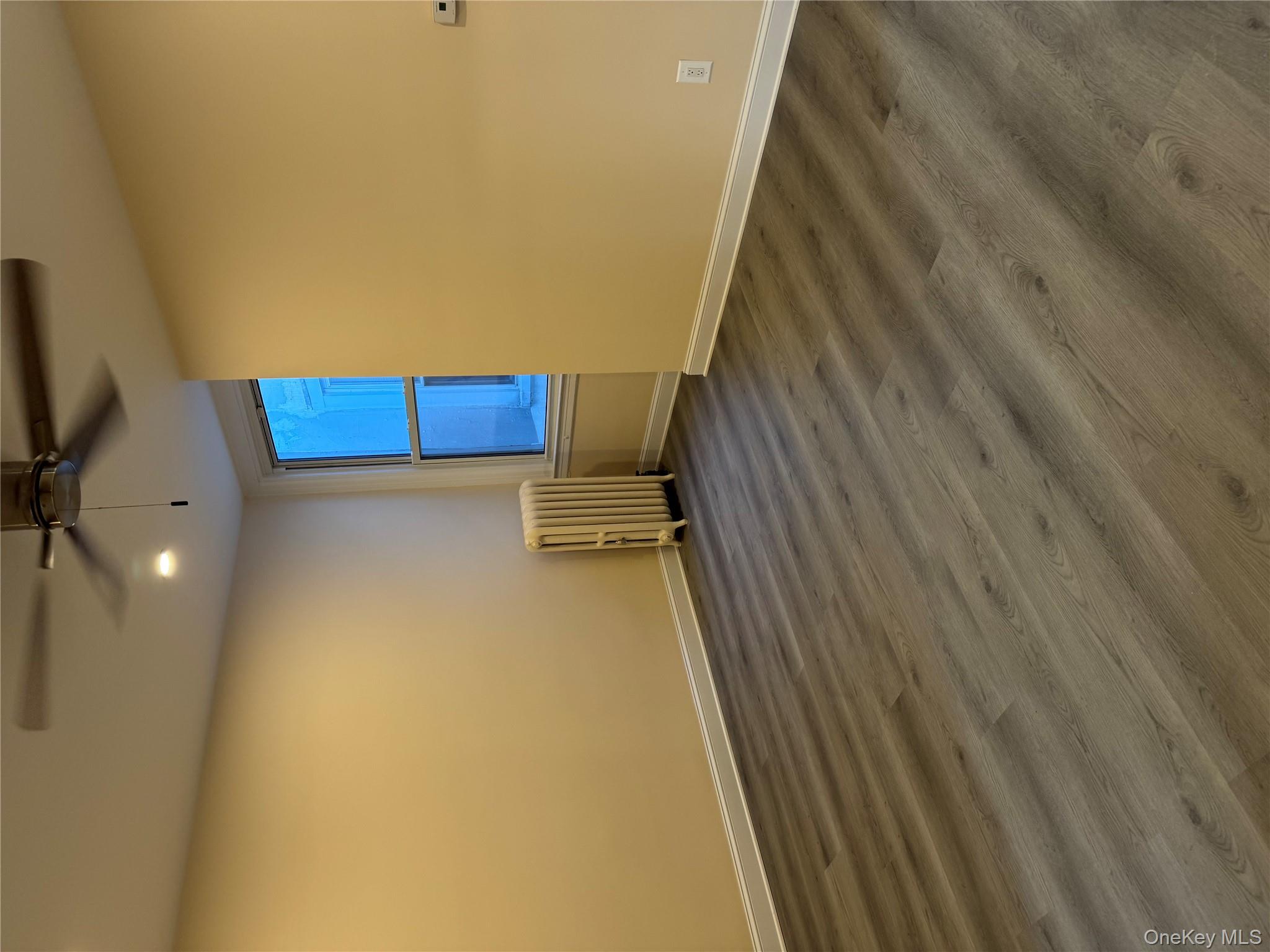 106-17 Metropolitan Avenue, Unit 1 Queens, NY 11375 - Photo 3 of 5 an empty room with wooden floor and windows