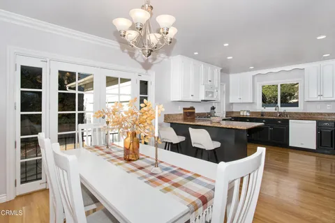 a kitchen with granite countertop stainless steel appliances a dining table and chairs
