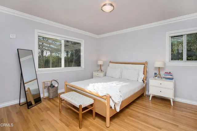 a bedroom with a bed a dresser and wooden floor