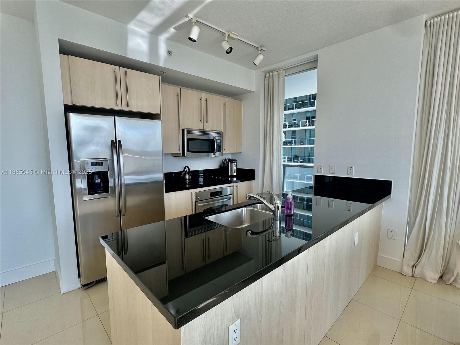 1111 Southwest 1st Avenue, Unit 1914 Miami, FL 33130 - Photo 2 of 31 a kitchen with stainless steel appliances granite countertop a sink and a refrigerator