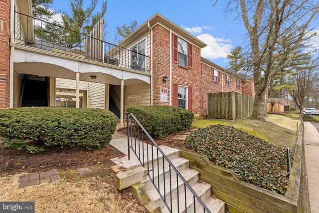 a view of a brick house with wooden fence next to a yard