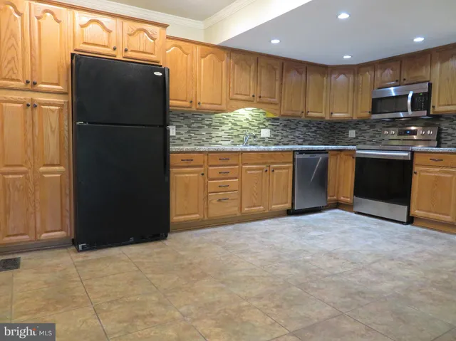 a kitchen with granite countertop a refrigerator and a stove top oven
