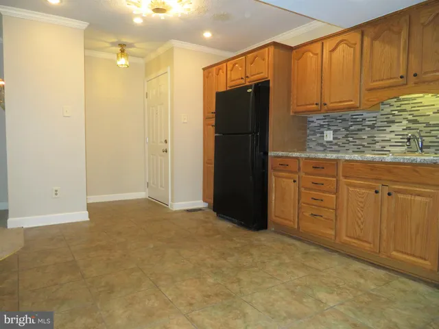 a view of kitchen with granite countertop cabinets and refrigerator