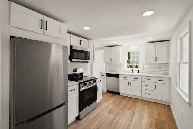a kitchen with granite countertop cabinets stainless steel appliances and wooden floor