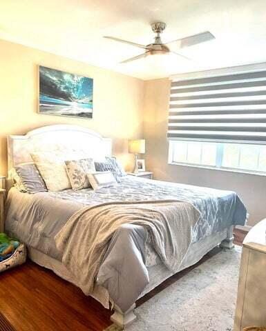 3111 Clint Moore Road, Unit 106 Boca Raton, FL 33496 - Photo 6 of 12 a bedroom with a bed and a chandelier